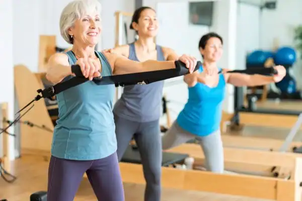 Toning Arms After 60: Empowering Womens Fitness Through Effective Weight Training 2 older woman doing weight training Brackley and resistance in the gym to tone upper arms