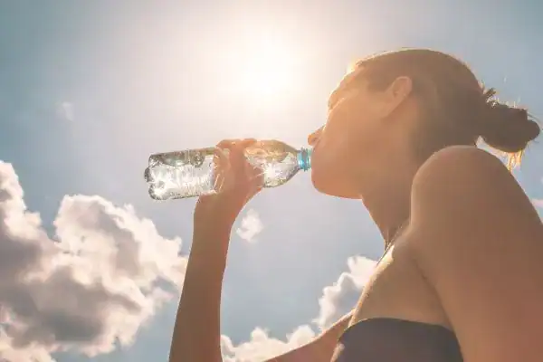 Hydration: The Secret Ingredient for a Toned Stomach and Enhanced Fitness 3 Image of woman drinking water to hydrate Brackley after run.