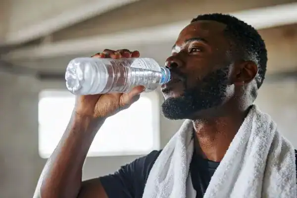 Hydration: The Secret Ingredient for a Toned Stomach and Enhanced Fitness 1 Image of man drinking water to improve hydration Brackley after work out.